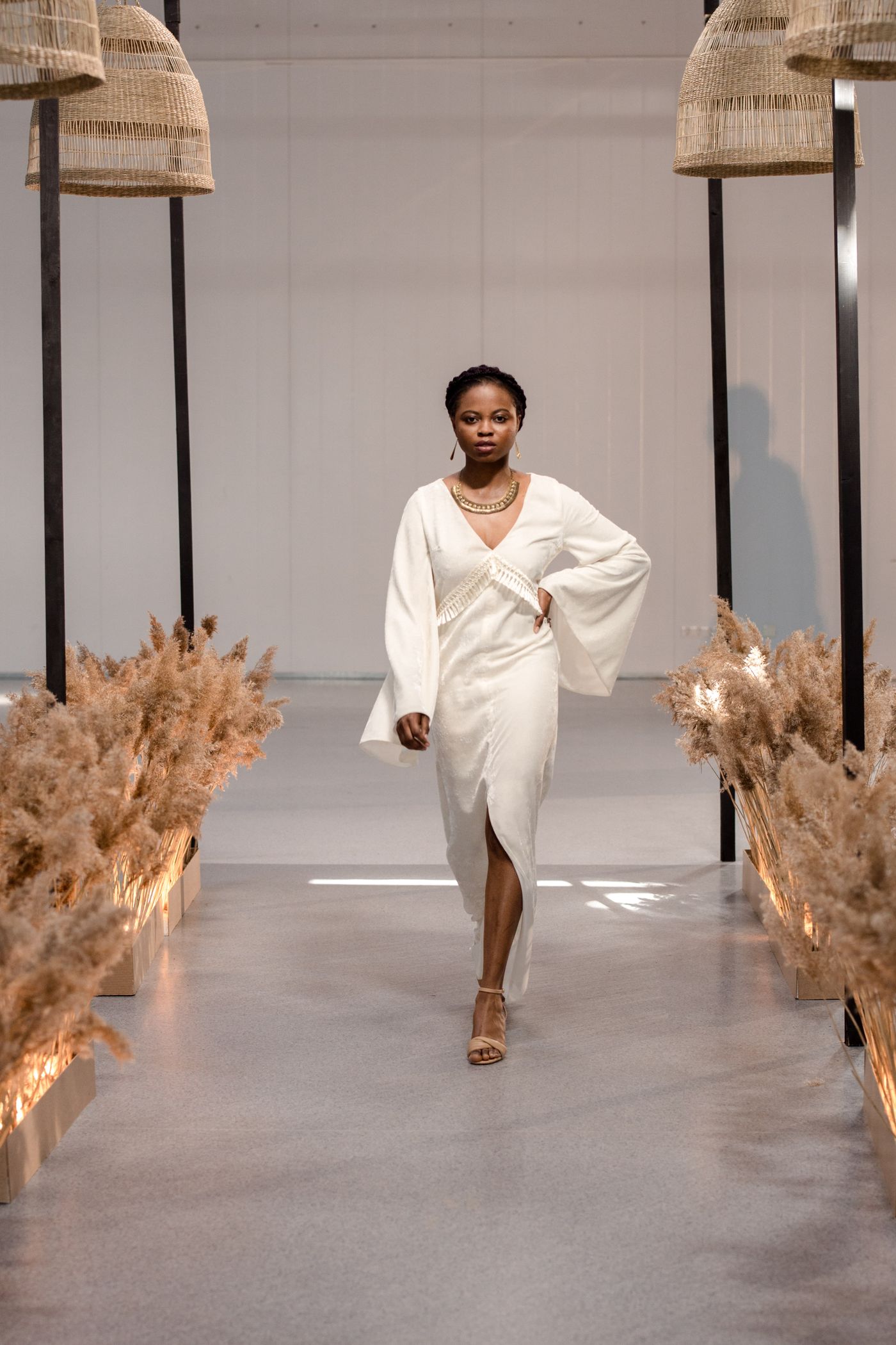 Model in a flowing white dress at a runway event